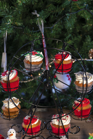 Various colorful Christmas cupcakes with christmas tree and wood backgroundの写真素材