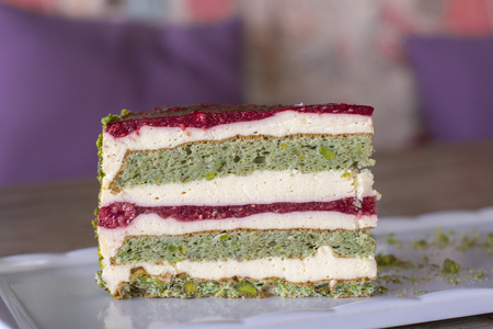 Pistachio and berry cake on white plate on wood table