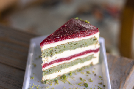 Pistachio and berry cake on white plate on wood tableの写真素材