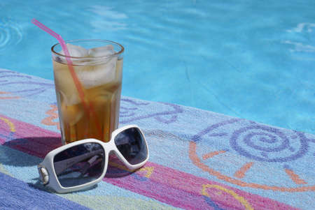 A glass of iced tea near the swimming pool.の写真素材