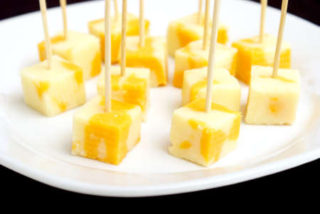 A plate of cheese cubes with toothpicks.の写真素材