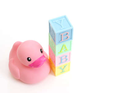 A pink rubber duck sits next to the word baby.の写真素材