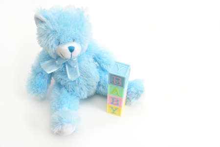 A blue teddy bear sits next to the word baby.の写真素材