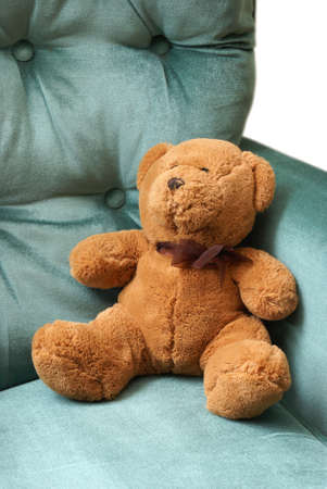 A brown teddy bear relaxes on a green chair.の写真素材