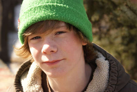 A close-up of a young teen boy outside.