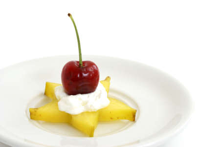 A piece of star-fruit with whipped cream and a cherry.の写真素材