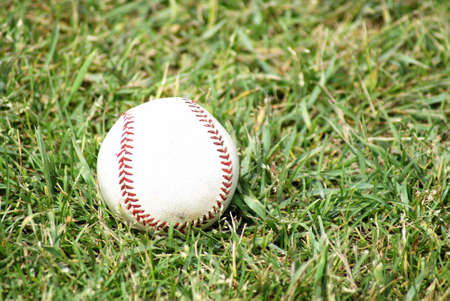 A pro baseball sits on the fields green grass.の写真素材