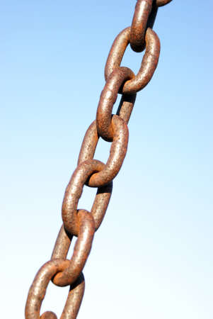 A rusted link of chain over a blue background.の写真素材