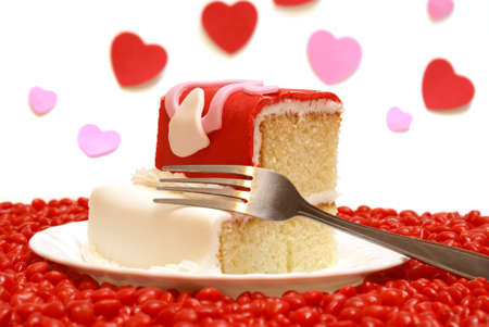 A slice of cake surrounded by candy hearts.