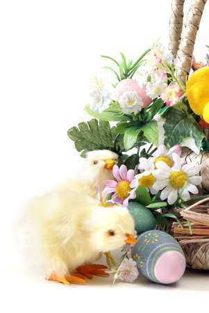 A couple of Easter chicks near a basket with flowers and eggs.の写真素材