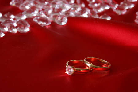 A couple of gold engagement rings with loose diamonds in the background for the symbol of wedded bliss.の写真素材