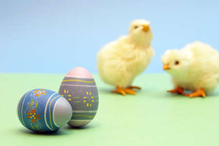A couple painted eggs are in focus while a couple chicks are blurred in the background.