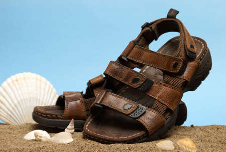 A fashionable shot of a pair of males leather sandals on a beach scene.の写真素材