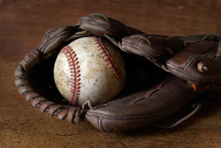 A low contrast image of a well used hardball and glove for those who love the sport of baseball.の写真素材
