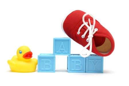 The word baby is isolated on white with a rubber ducky and a red shoe.の写真素材