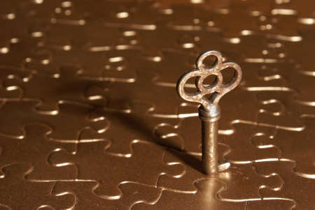 A rustic skeleton key on top of a golden puzzle.              の写真素材