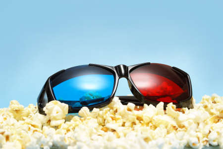 A pair of sleek 3D glasses rests on top of a pile of fresh popcorn.