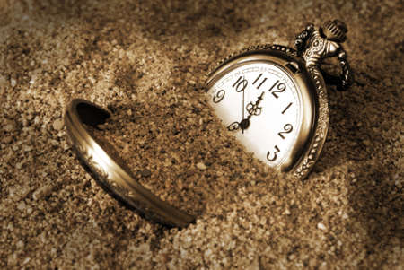 A pocket watch is buried in the dirty sand.の写真素材
