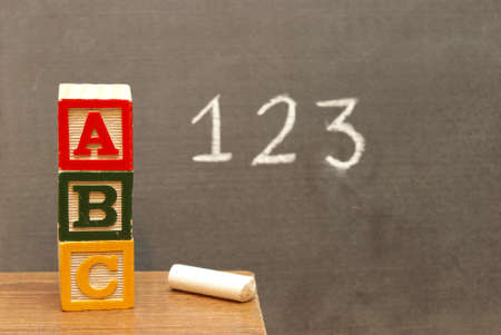 Alphabet blocks and numbers wrote on the chalkboard for learning the basics of the english language.