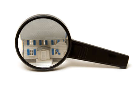 A home inspection concept using a model house and a magnifying glass.の写真素材