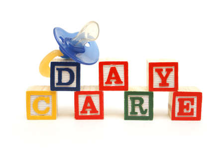 An infants pacifier next to the words day care.の写真素材
