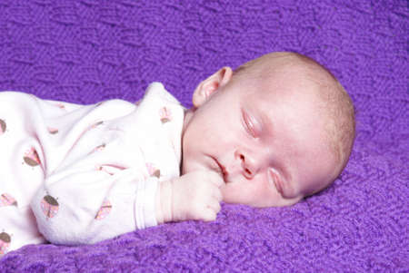 A one month old baby girl is sleeping peacefully.の写真素材