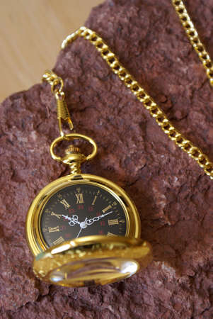 A gold pocket watch on a red sandstone.の写真素材