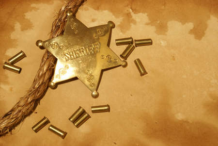 A sheriff badge and gun shells on some antique paper.の写真素材