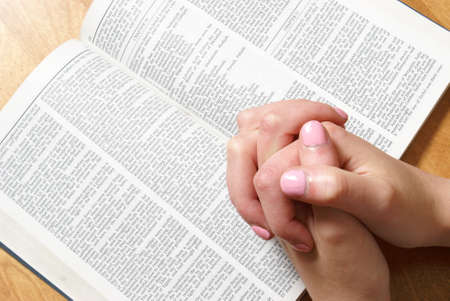 A young woman faithfully prays with her bible open.