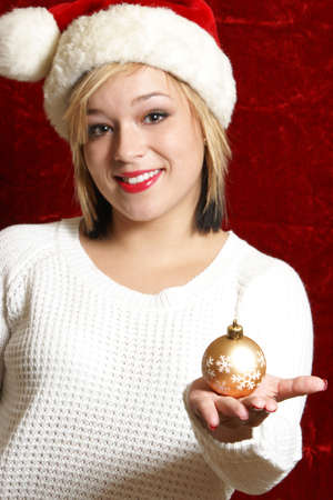 A beautiful woman holds a Christmas bauble as she gets ready to decorate.の写真素材
