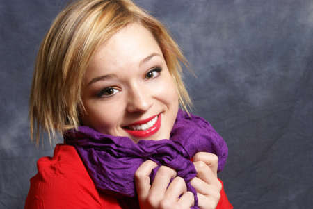 A young woman scrunches her scarf in a warm fashionable pose.