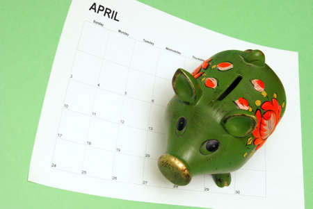 A pig bank and calendar represent the tax season.の写真素材