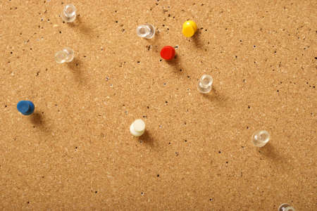 Various pins stuck into a corkboard for office use.