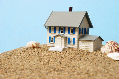 A closeup shot of a model house in the sand for waterfront property concepts.の写真素材