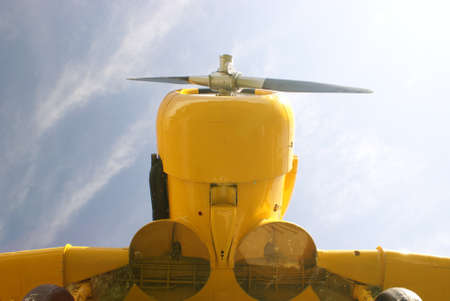 A closeup shot of a yellow plane from underneath with the blue sky in the background.の写真素材