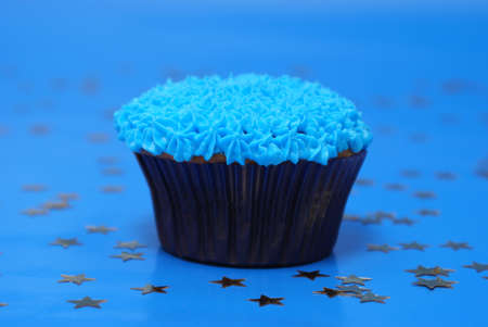 A frosted cupcake on a blue background.の写真素材
