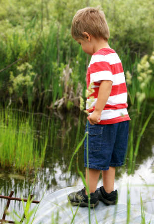 A happy two year old boy sparks curiousity at a nearby culvert while searching for tadpoles, frogs, and fish.の写真素材
