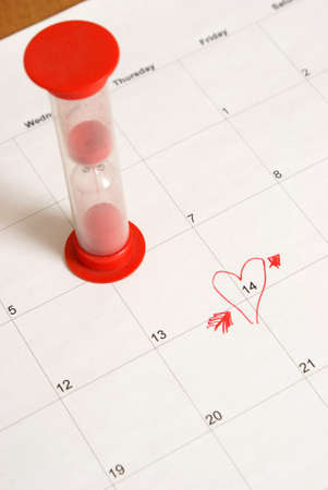 An hourglass and reminder on a calendar for the upcoming Valentines Day.