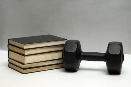 A dumbbell and stack of books for the concept of learning to be fit and healthy.の写真素材