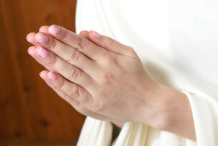 A young woman brings her hands together in prayer to the almighty father in heaven.の写真素材
