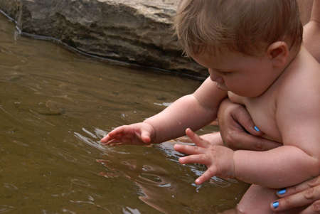 A young boy sitting in the water near shore.の写真素材