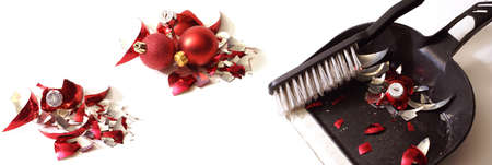 A smashed red holiday bauble has fallen to many pieces so a broom and dustpan come to clean up the mess.の写真素材