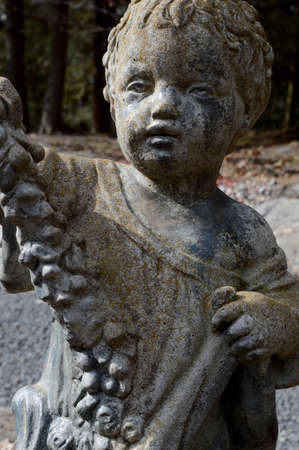 A cute boy stone statue graces the garden.の写真素材