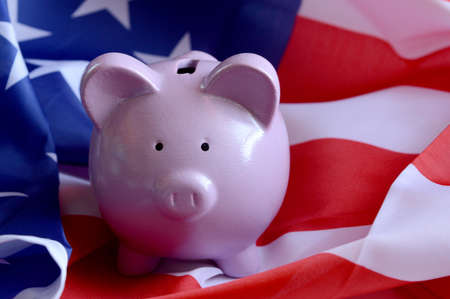 Closeup view of an American flag with a pink piggy bank for various financial concepts.の写真素材