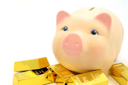 Closeup view of several gold bullion bars next to a piggy bank.の写真素材