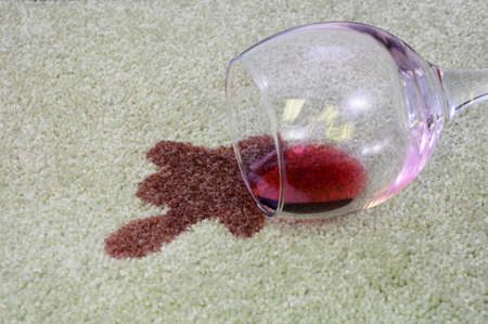A glass of red wine has been spilled onto a white carpet.の写真素材