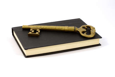 A large key ontop of an isolated book for concepts of literary success.の写真素材