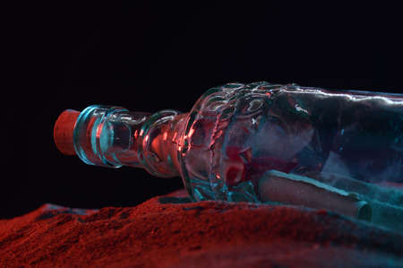 A closeup low angle shot of a message in a bottle revealed in the sandy shoreline during the night time light.の写真素材