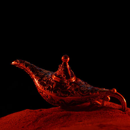 A magical genie lamp is revealed in the surface of the sand during the late hours of the evening.の写真素材
