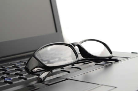 A pair of reading glasses set on a laptop for better screen viewing.の写真素材